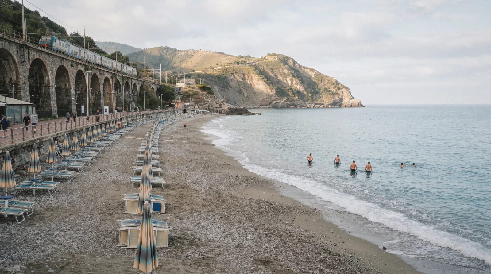 Fegina beach at Monterosso al Mare in the morning with the railway viaduct behind and Punta Mesco at the end of the bay, Cinque Terre, Italy