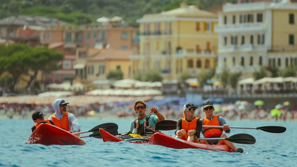 Guide leading a kayak tour along the coast from Monterosso to Vernazza in Cinque Terre