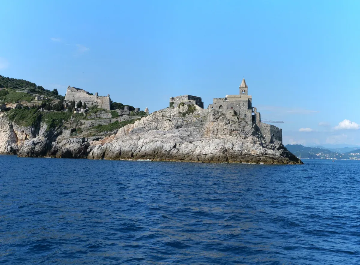 Doria Castle and the striped bell tower of San Pietro church on the Portovenere promontory, Italy