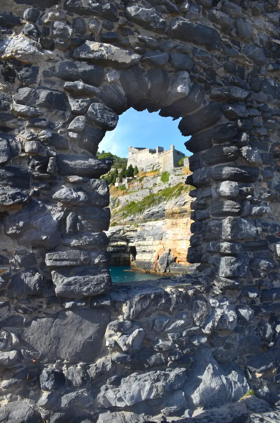 View through a stone wall opening of Doria Castle above Portovenere's cliffs, Italy